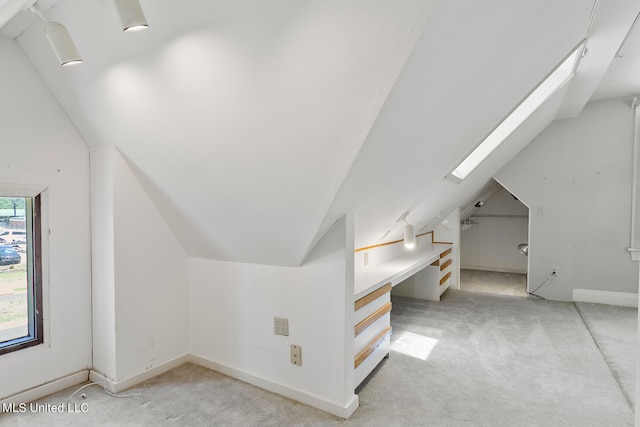 bonus room featuring lofted ceiling with skylight and light colored carpet