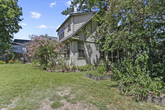 1521 Riverside Dr, Jackson, MS 39202 - view of side of home with a vegetable garden, a yard, stucco siding, and fence