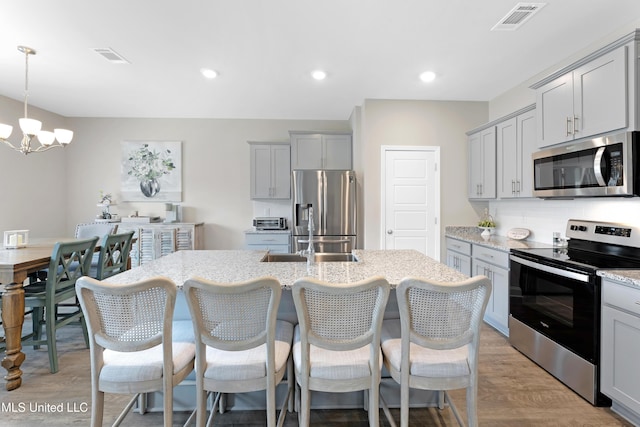 19489 Little Manatee St, Biloxi, MS 39532 - kitchen with stainless steel appliances, gray cabinetry, a chandelier, light stone countertops, and recessed lighting