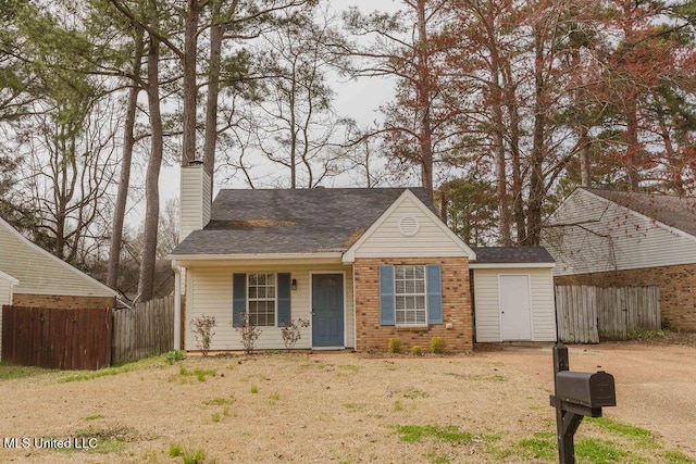 view of front of home with brick siding, a chimney, and fence