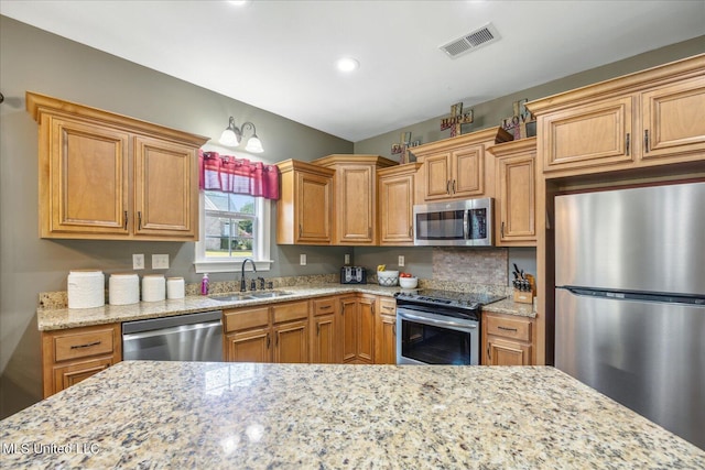 kitchen with sink, light stone countertops, and stainless steel appliances