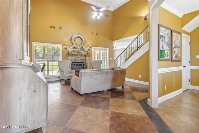 living room with a towering ceiling, crown molding, ornate columns, and ceiling fan