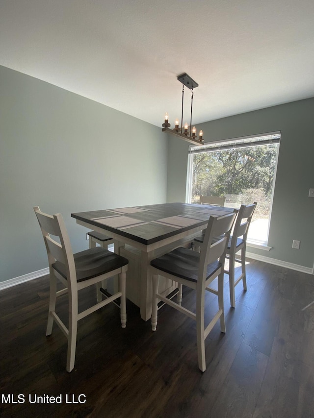 dining room featuring a notable chandelier, baseboards, and wood finished floors