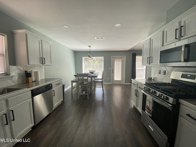 kitchen featuring tasteful backsplash, baseboards, visible vents, dark wood finished floors, and stainless steel appliances