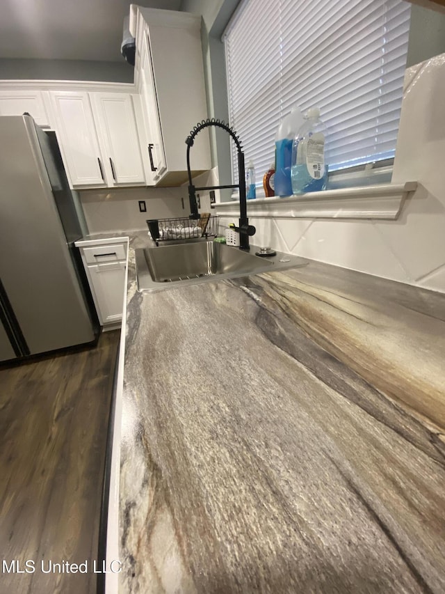 kitchen featuring white cabinetry, dark wood finished floors, a sink, and freestanding refrigerator