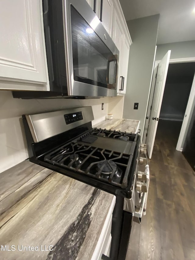 kitchen with appliances with stainless steel finishes, dark wood-type flooring, and white cabinets