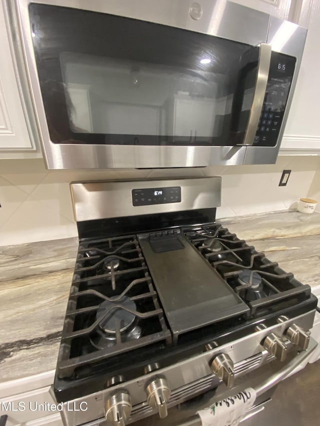 kitchen with appliances with stainless steel finishes, decorative backsplash, and white cabinets