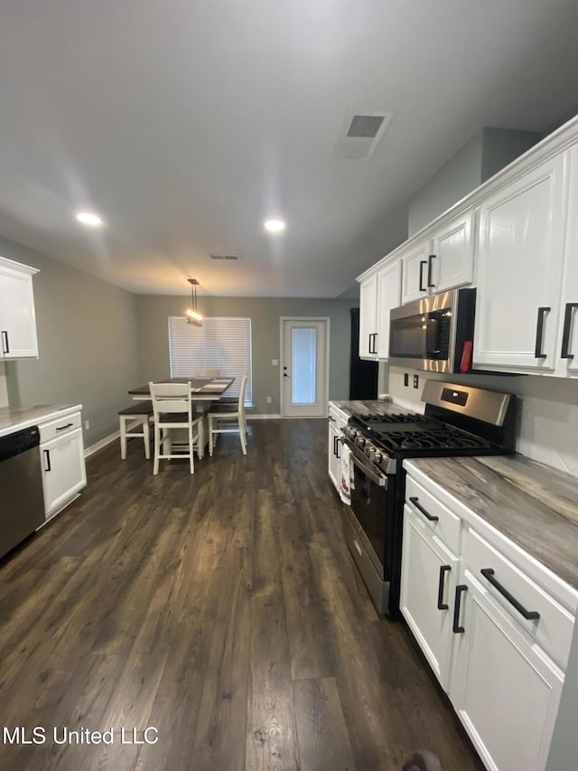 kitchen with appliances with stainless steel finishes, white cabinetry, dark wood finished floors, and visible vents