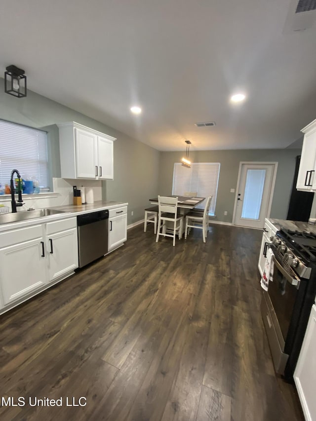 kitchen with dark wood-style floors, visible vents, appliances with stainless steel finishes, white cabinetry, and a sink