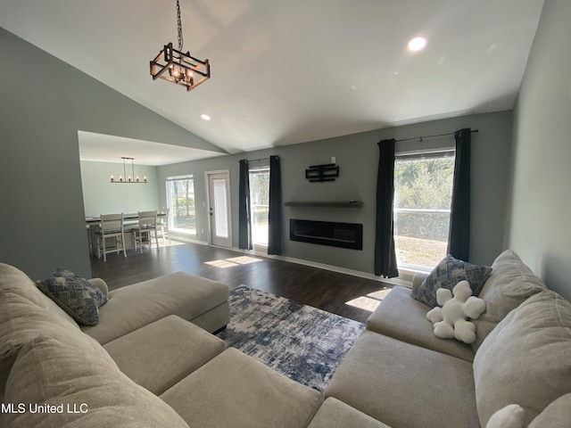 living area with a glass covered fireplace, wood finished floors, vaulted ceiling, and an inviting chandelier