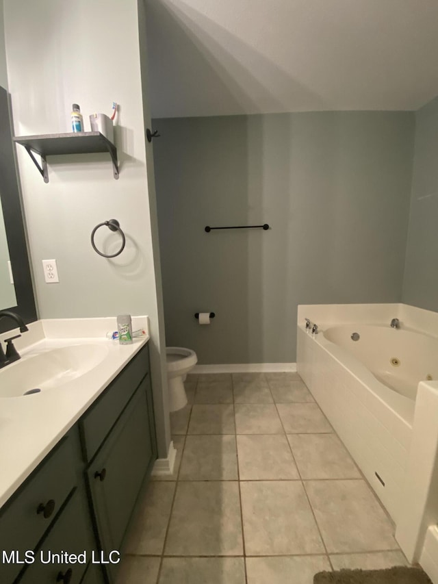 bathroom with baseboards, toilet, a whirlpool tub, tile patterned flooring, and vanity