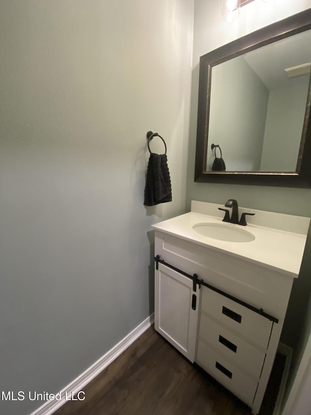 bathroom with baseboards, wood finished floors, and vanity