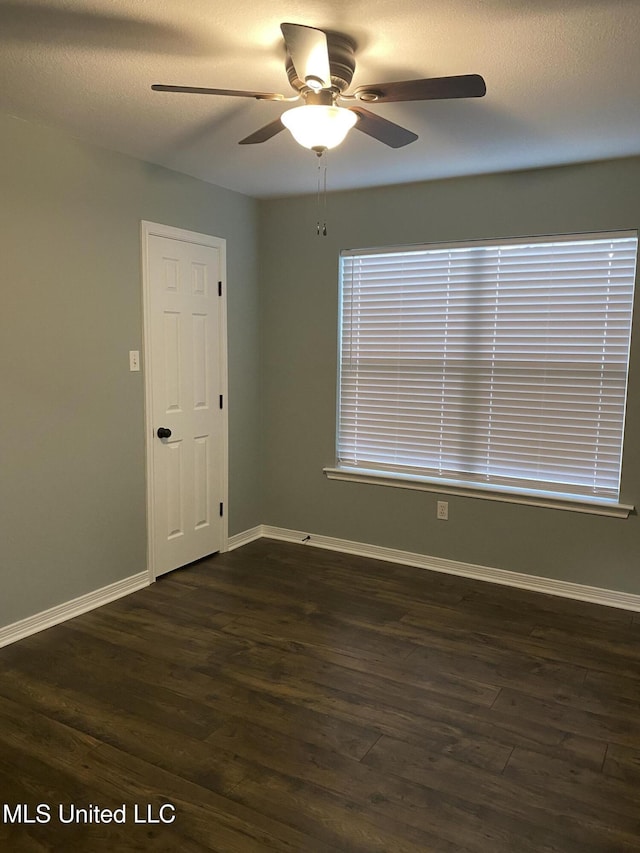 unfurnished room featuring dark wood-style floors, ceiling fan, a textured ceiling, and baseboards