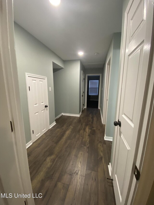 corridor with baseboards and dark wood finished floors