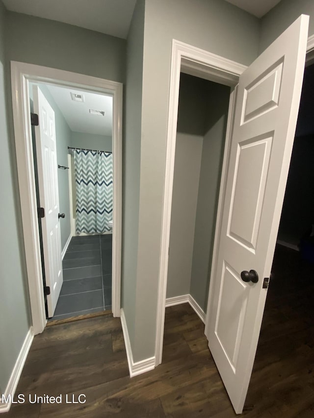 corridor featuring baseboards and dark wood finished floors