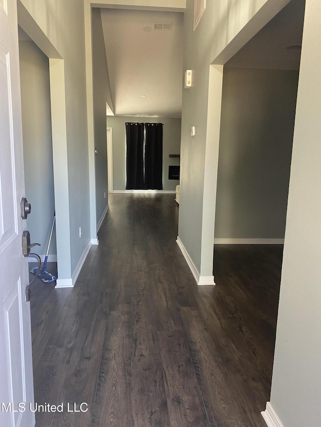 corridor with dark wood-type flooring, visible vents, and baseboards