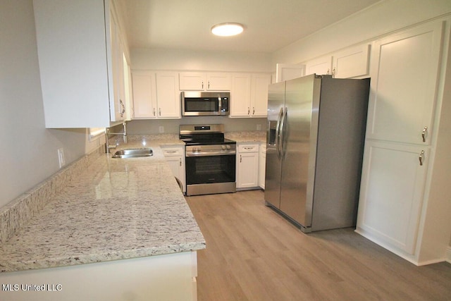 136 Childress Rd, Lucedale, MS 39452 - kitchen with stainless steel appliances, a sink, white cabinets, light wood-style flooring, and light stone counters