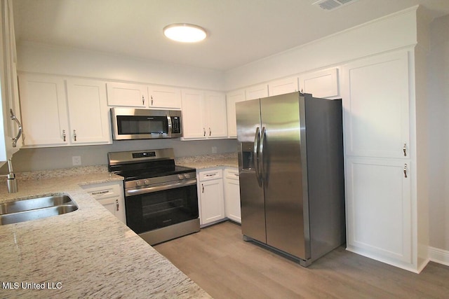 136 Childress Rd, Lucedale, MS 39452 - kitchen featuring appliances with stainless steel finishes, light wood-style floors, a sink, and white cabinets