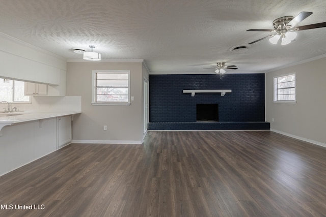 unfurnished living room featuring a textured ceiling, dark wood finished floors, and ornamental molding