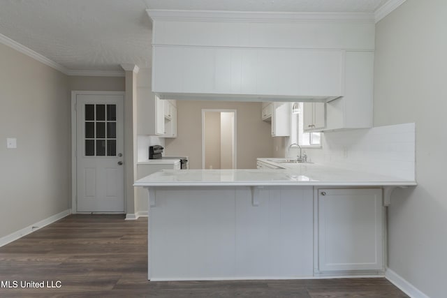 kitchen featuring stainless steel electric range oven, a peninsula, ornamental molding, a sink, and dark wood-type flooring