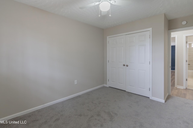 unfurnished bedroom featuring carpet, baseboards, a closet, and a textured ceiling