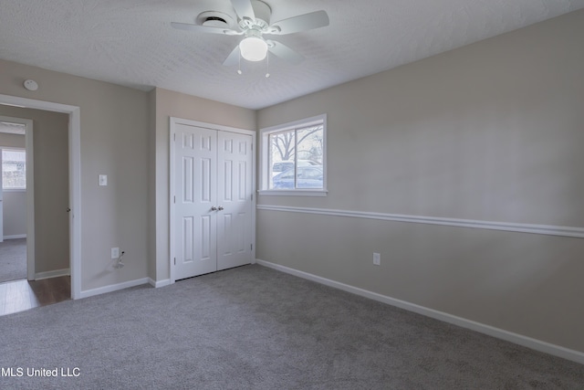 unfurnished bedroom featuring multiple windows, a textured ceiling, baseboards, and carpet