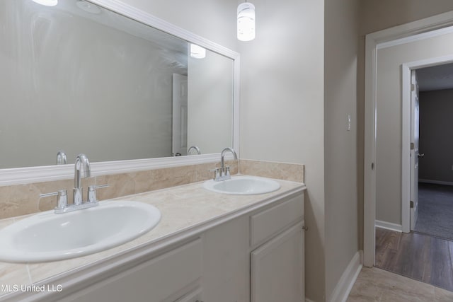 full bathroom featuring a sink, baseboards, and double vanity