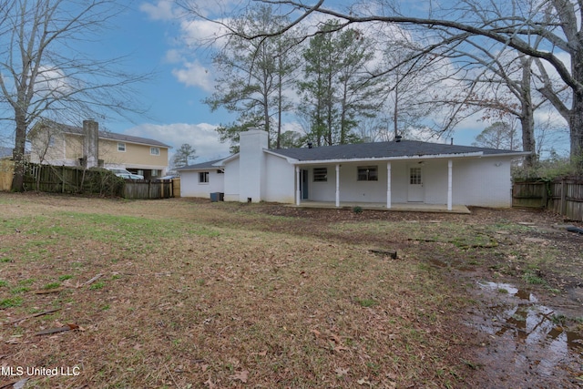 back of house featuring a patio area, a lawn, a chimney, and fence