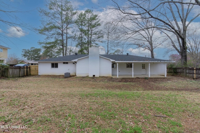 rear view of property featuring a lawn, a fenced backyard, a chimney, and a patio area