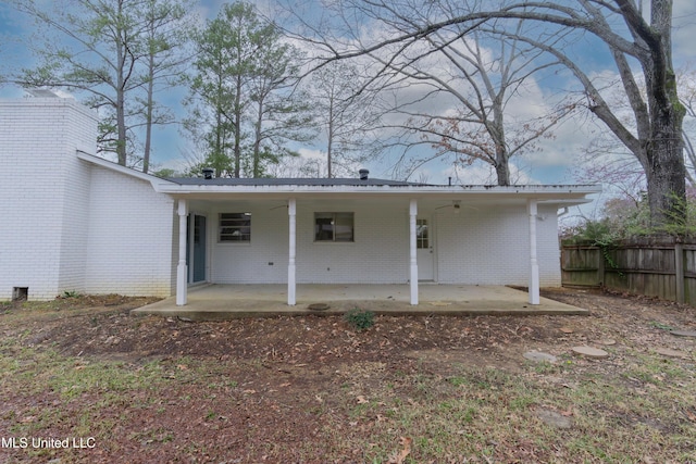 rear view of house with a ceiling fan, fence, a chimney, a patio area, and brick siding