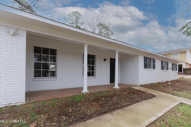 property entrance featuring a porch and brick siding