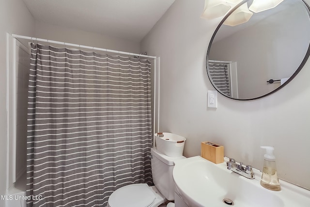 bathroom featuring toilet, sink, and curtained shower