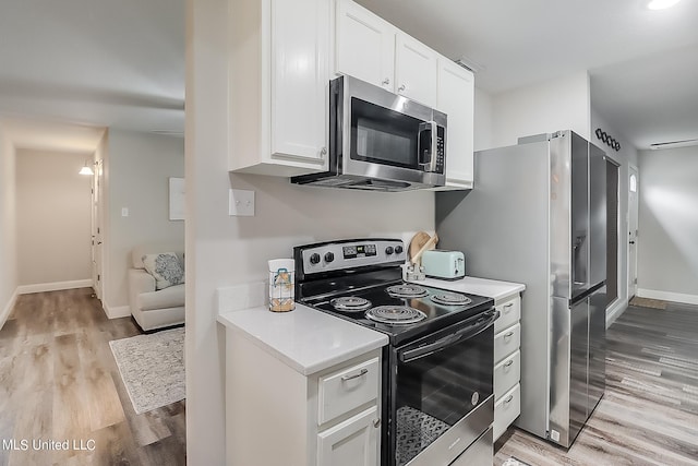 kitchen with stainless steel appliances, light hardwood / wood-style flooring, and white cabinets