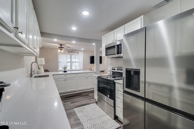 kitchen with dark hardwood / wood-style floors, sink, white cabinets, appliances with stainless steel finishes, and ceiling fan