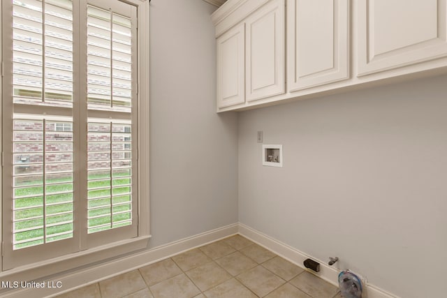 clothes washing area with washer hookup, light tile patterned floors, and cabinets