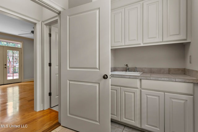 clothes washing area featuring sink, light wood-type flooring, french doors, ceiling fan, and ornamental molding