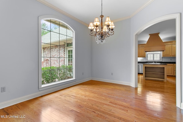 unfurnished dining area with sink, crown molding, a notable chandelier, and light wood-type flooring