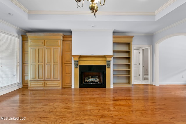 unfurnished living room featuring ornamental molding, a tray ceiling, and light wood-type flooring