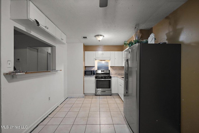 791 Leach St, Yazoo City, MS 39194 - kitchen featuring stainless steel appliances, white cabinetry, light tile patterned floors, baseboards, and a textured ceiling