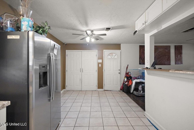 791 Leach St, Yazoo City, MS 39194 - kitchen with stainless steel fridge, white cabinets, ceiling fan, light tile patterned flooring, and a textured ceiling