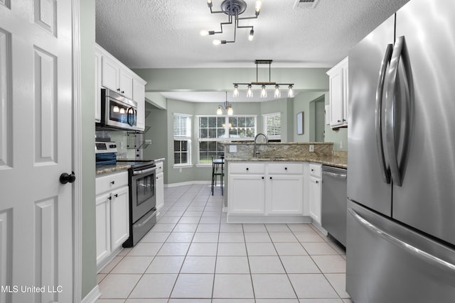 kitchen with stainless steel appliances, white cabinetry, kitchen peninsula, and pendant lighting