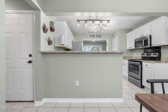 kitchen featuring light stone counters, kitchen peninsula, stainless steel appliances, light tile patterned floors, and white cabinets