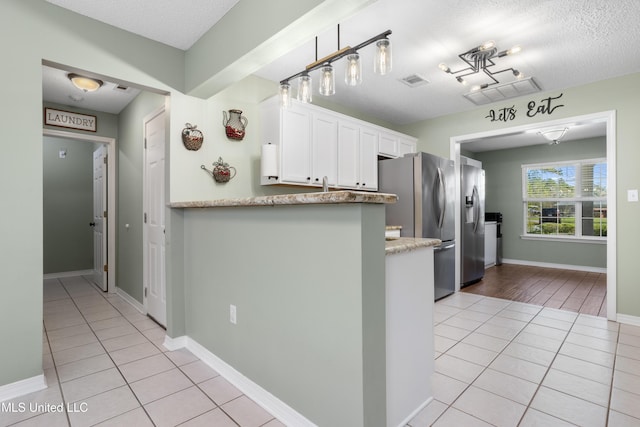 kitchen with a textured ceiling, white cabinetry, light tile patterned floors, and hanging light fixtures