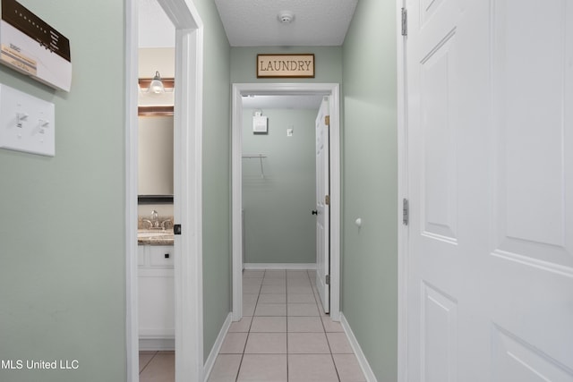 hallway featuring a textured ceiling, sink, and light tile patterned floors