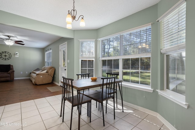 dining area featuring ceiling fan with notable chandelier, a textured ceiling, and light tile patterned flooring