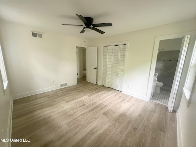 unfurnished bedroom featuring light wood-type flooring, a closet, baseboards, connected bathroom, and ceiling fan