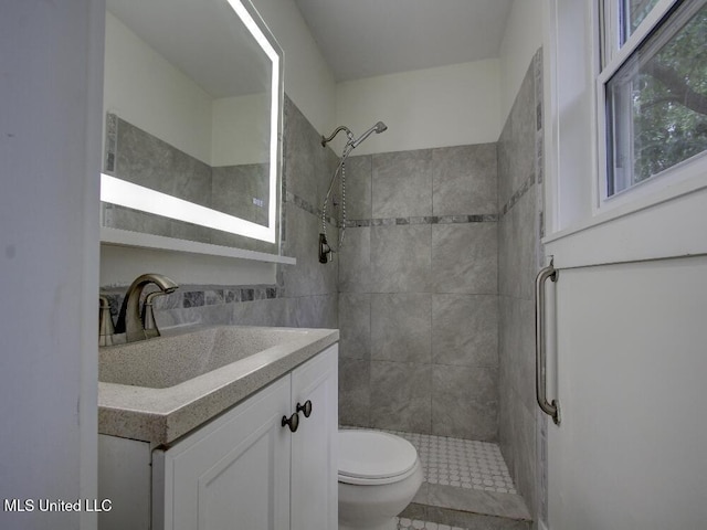 full bath featuring toilet, a tile shower, and vanity