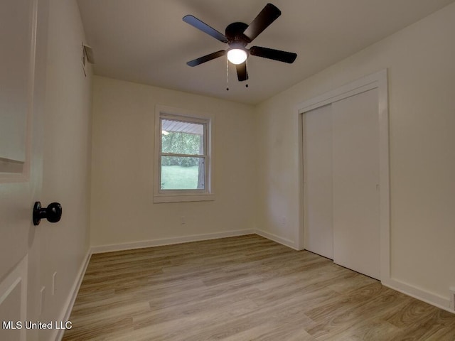unfurnished bedroom with light wood finished floors, a closet, baseboards, and ceiling fan