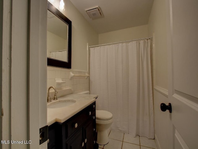 full bathroom with tile patterned floors, toilet, vanity, tile walls, and wainscoting