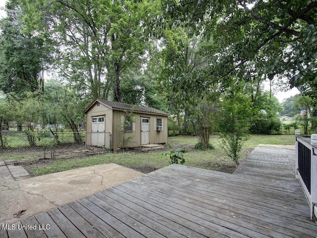 deck with a storage shed, fence, an outbuilding, and view of wooded area